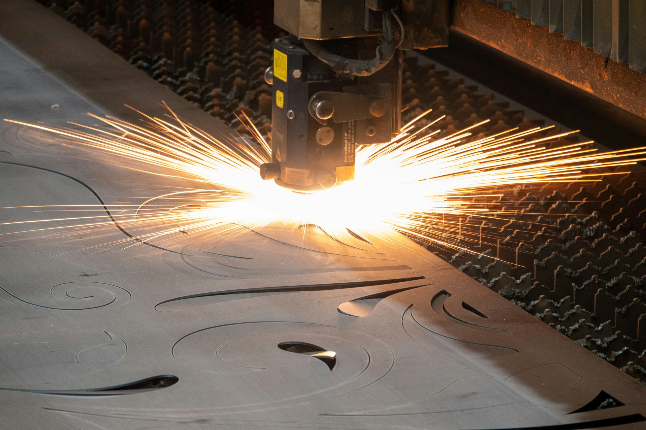 CO2 laser in action carving an ornamental design in a sheet of plastic.